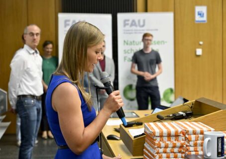 StRin Stefanie Senft (FAU) bei der Laudatio Informatik, im Hintergrund Prof. Dr. Julien Bachmann (FAU) und Teilnehmende des Fachs Informatik (Foto: Harald Sippel / FAU)